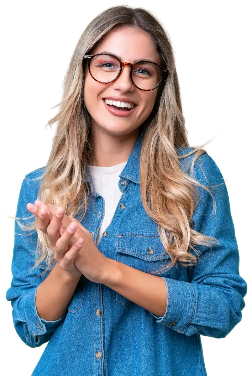 Smiling young woman with long blonde hair wearing glasses and a blue denim shirt, clapping her hands.